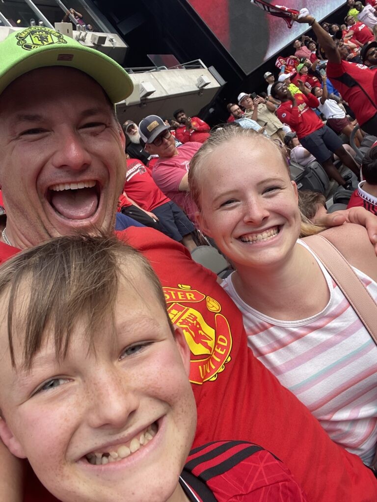 Robert with Kenley and Braden cheering at Manchester United